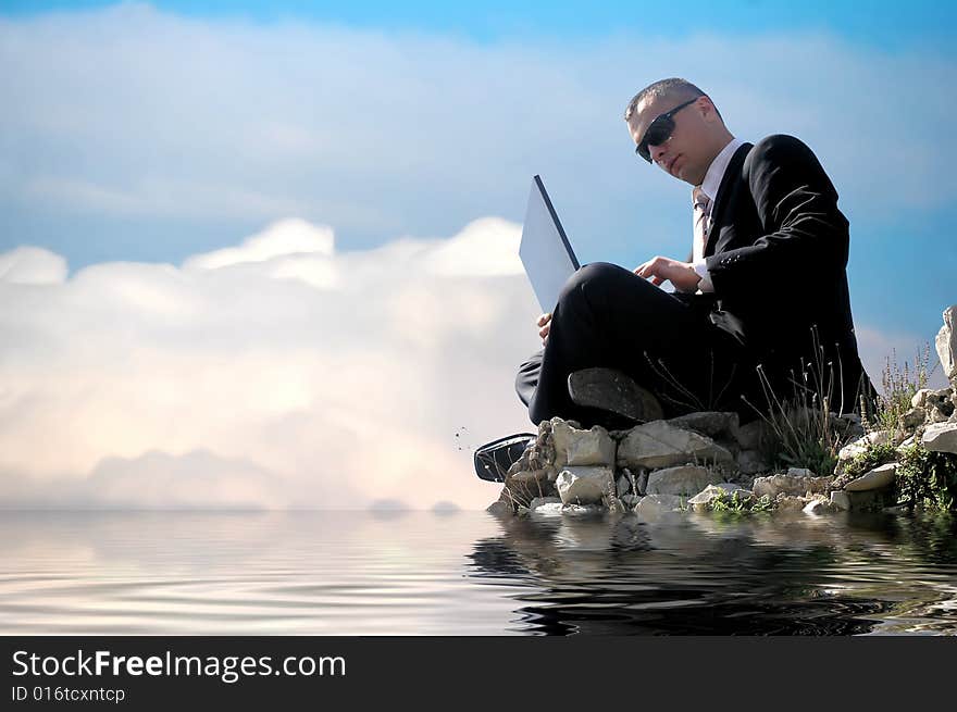 Men with his laptop working on a stone wall above water level