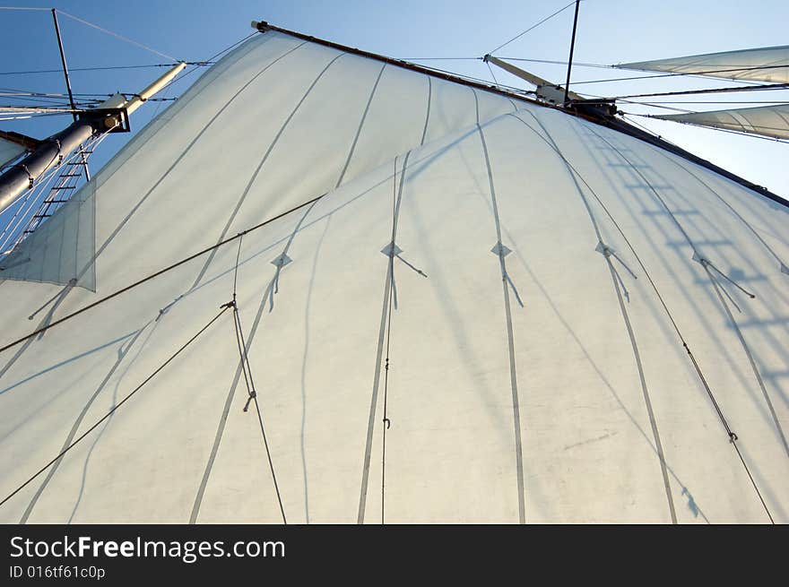 Big sail and Canadian flag on blue sky background