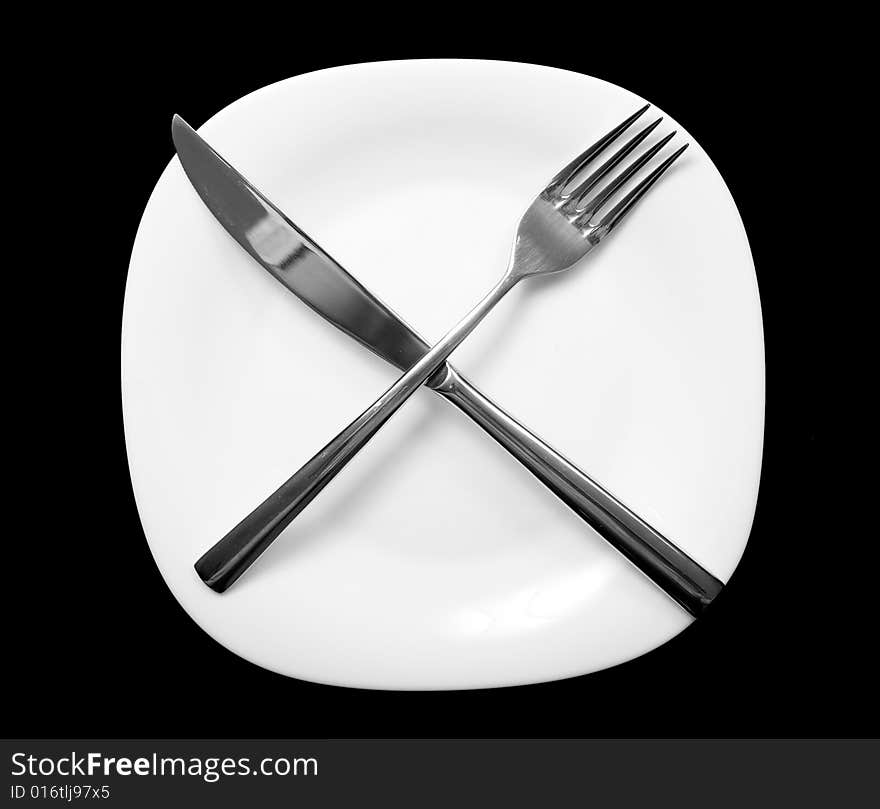 Fork and knife on plate. Black background.