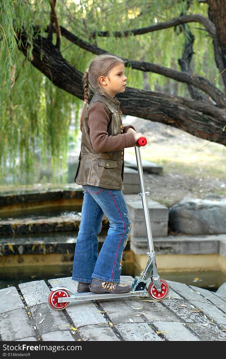 Little girl with scooter staying fon the footbridge. Little girl with scooter staying fon the footbridge