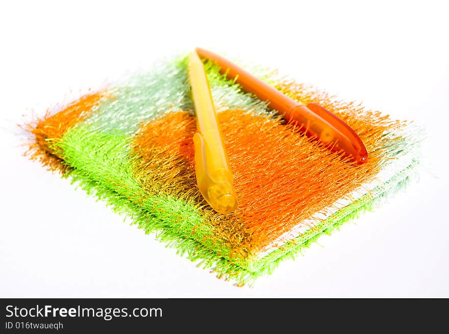 Notebook made of soft fabric with colorful pens on it, isolated on white background. Notebook made of soft fabric with colorful pens on it, isolated on white background