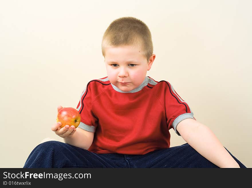 Boy in red little shirt eating the apple. Boy in red little shirt eating the apple