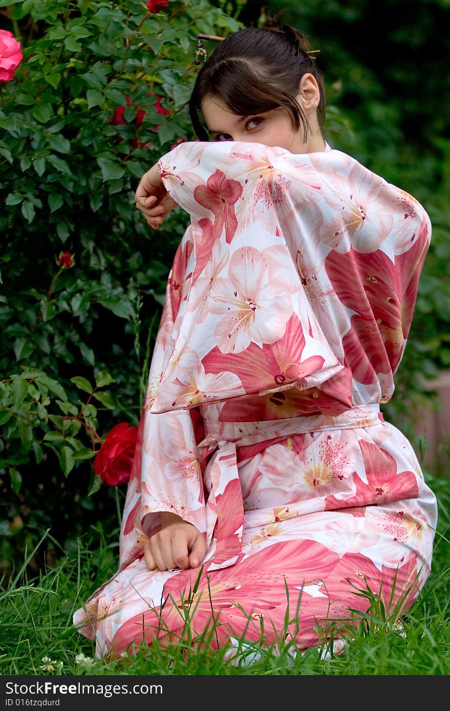 Girl in a pink yukata near rosebush. Girl in a pink yukata near rosebush