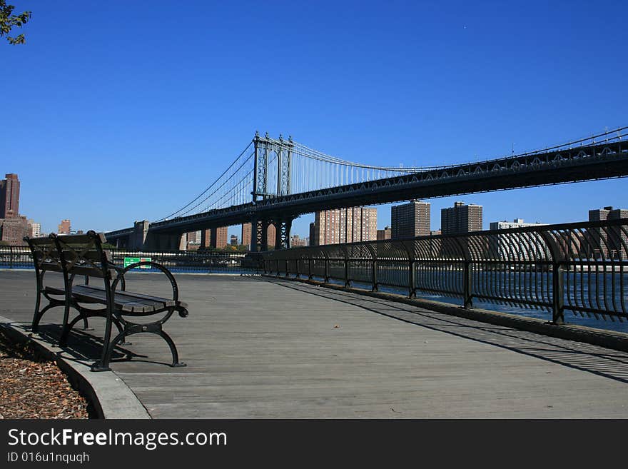 Park benche along the East River in Brooklyn.  Manhattan Bridge in the background.