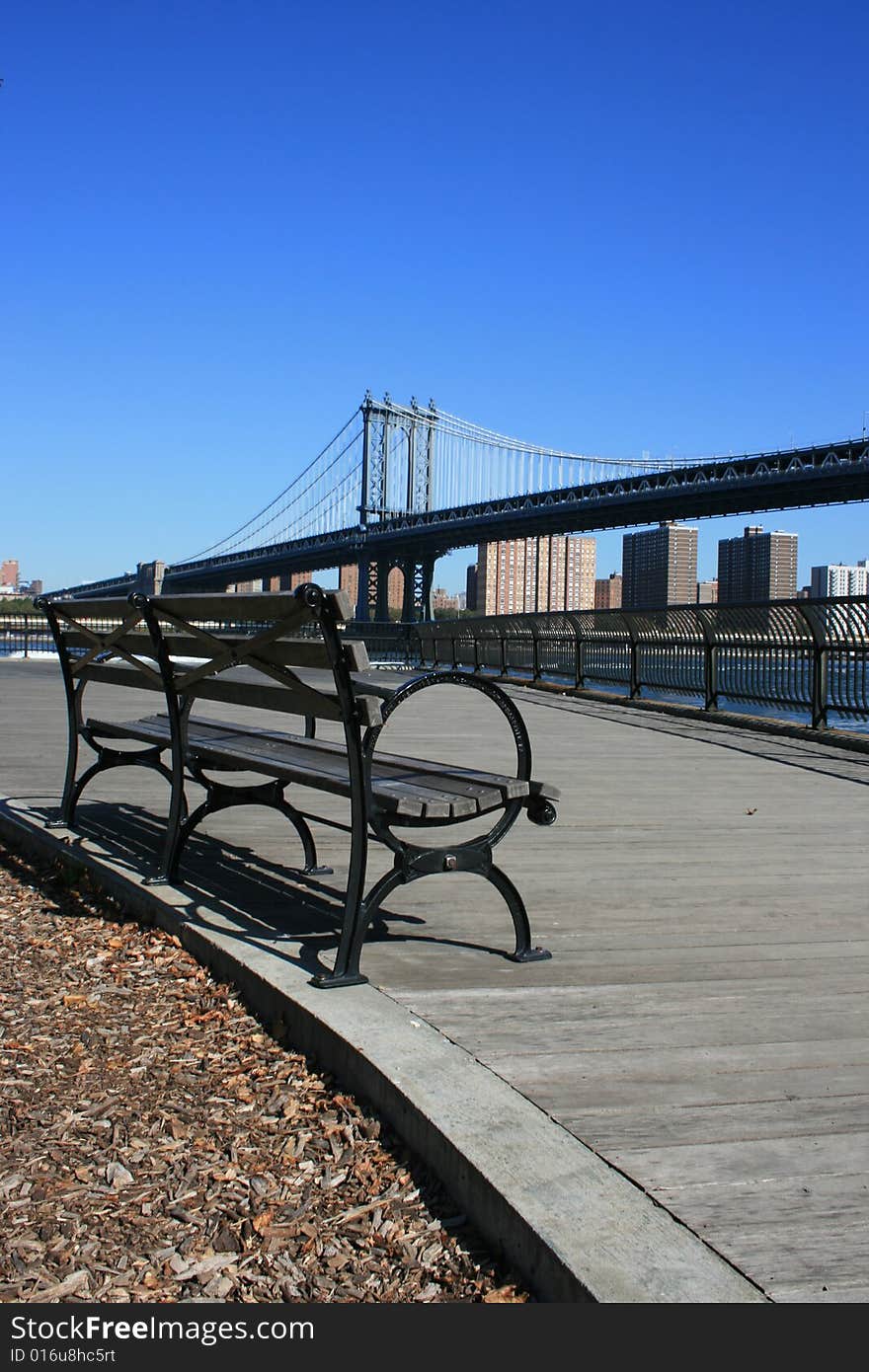 Park bench along the East River in Brooklyn.  Manhattan Bridge in the background. Park bench along the East River in Brooklyn.  Manhattan Bridge in the background.