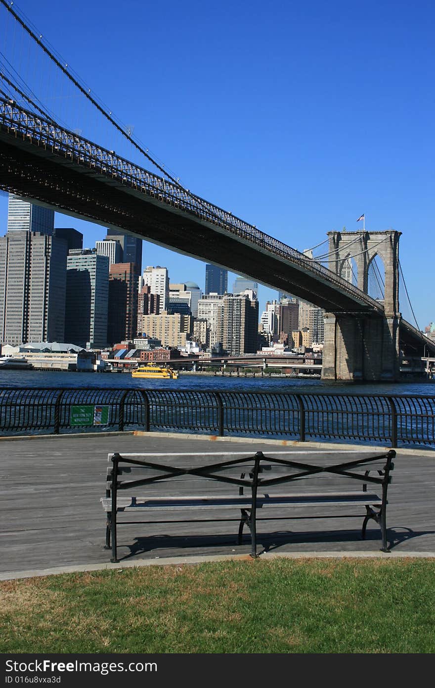 Park bench along the East River in Brooklyn. Lower Manhattan and Brooklyn Bridge in the background. Park bench along the East River in Brooklyn. Lower Manhattan and Brooklyn Bridge in the background.