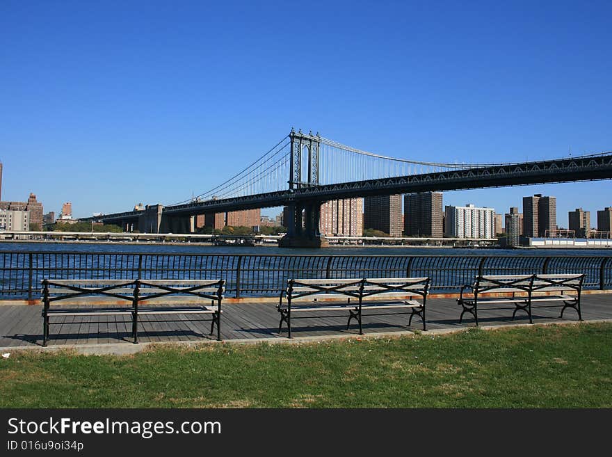 Park benches along the East River in Brooklyn. Manhattan Bridge in the background.