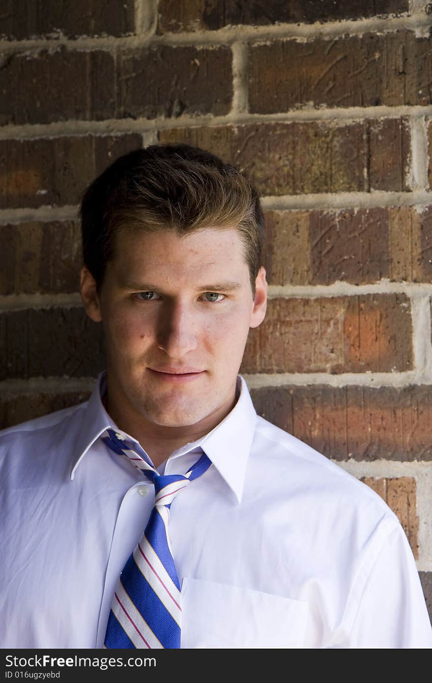 A casual young man leaning against a brick wall. A casual young man leaning against a brick wall