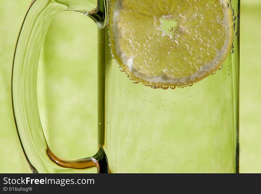 Lemon slice floating in a transparent glass full with sparkling water (club soda). Lemon slice floating in a transparent glass full with sparkling water (club soda)