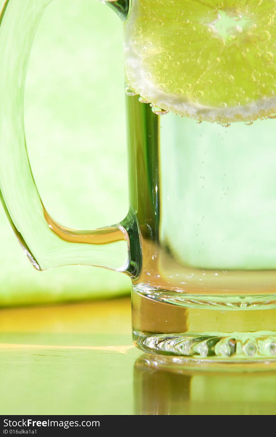 Lemon slice floating in a transparent glass full with sparkling water (club soda). Lemon slice floating in a transparent glass full with sparkling water (club soda)