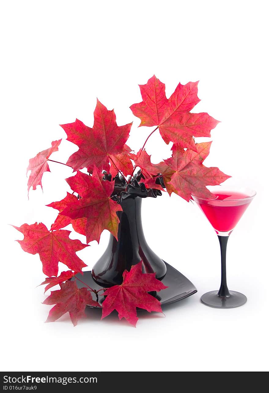 Beautiful red autumn leaves of maple and glass with red wine on white background