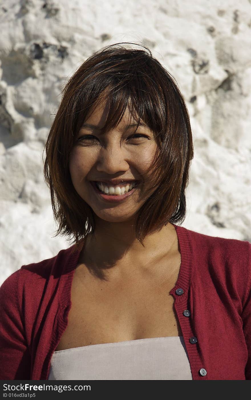 Happy smiling Asian woman at seaside. Shot at against White chalk cliffs.