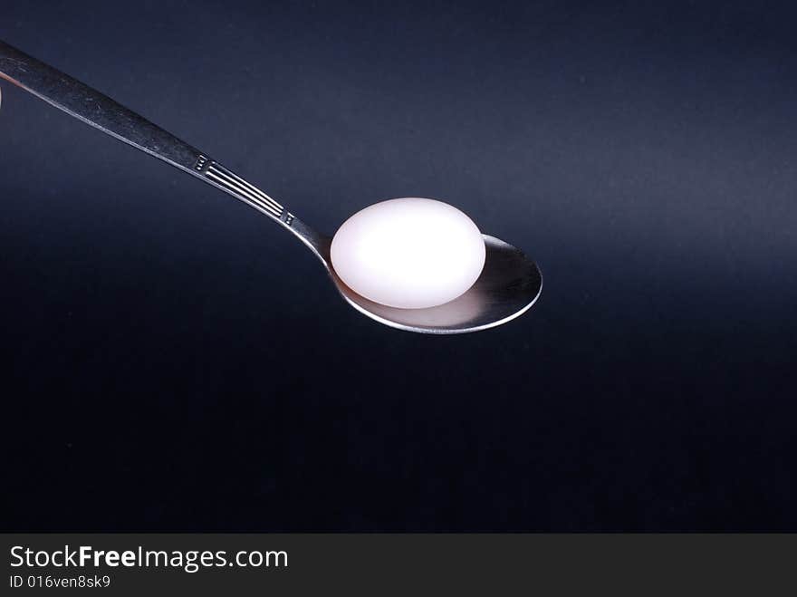 Egg and spoon on black background