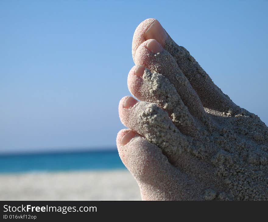 Female foot covered with sand