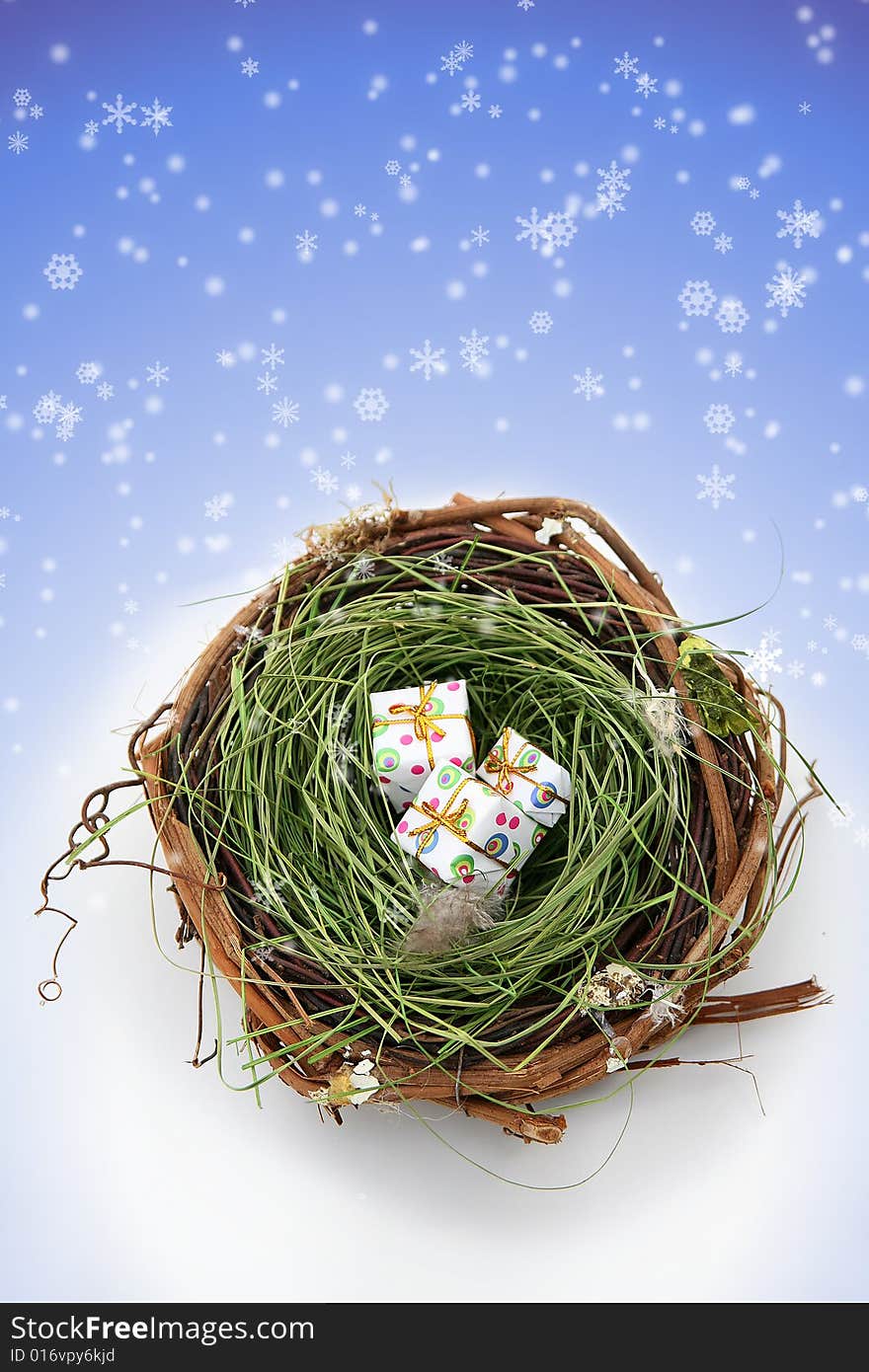 Conceptual image showing three presents in a bird's nest against a snowy background. Space for copy. Conceptual image showing three presents in a bird's nest against a snowy background. Space for copy.