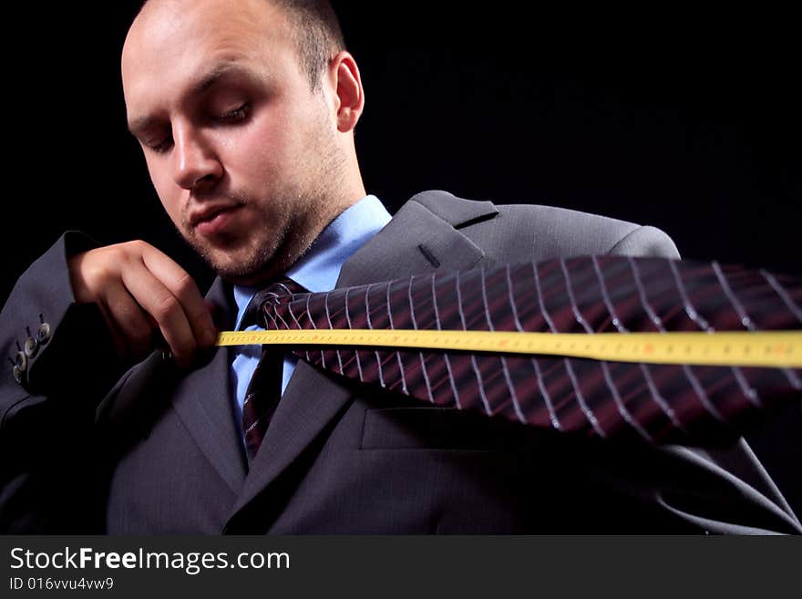 Man, dressed in a business suit, measures the tie. Man, dressed in a business suit, measures the tie