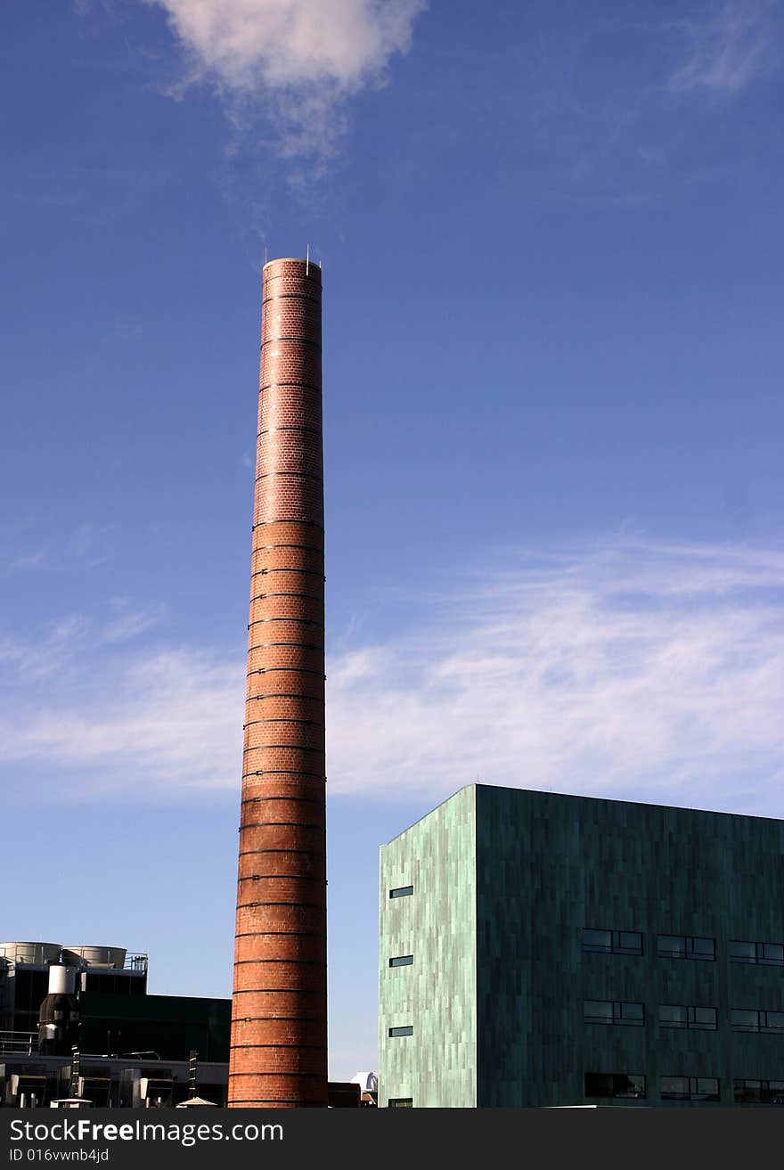 A singular brick steam stack in front of a blue sky. A singular brick steam stack in front of a blue sky