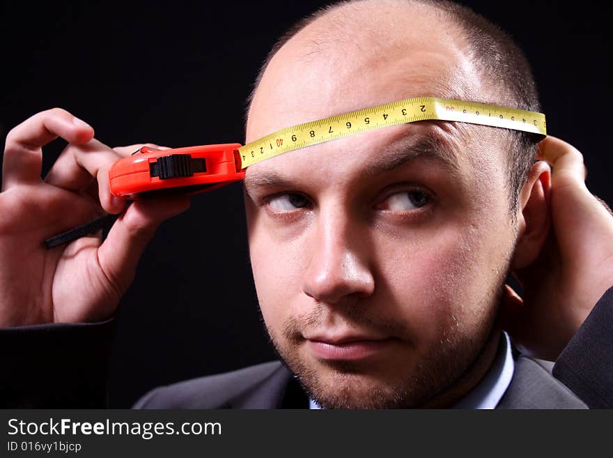 Serious the man measures the head by a roulette. Serious the man measures the head by a roulette