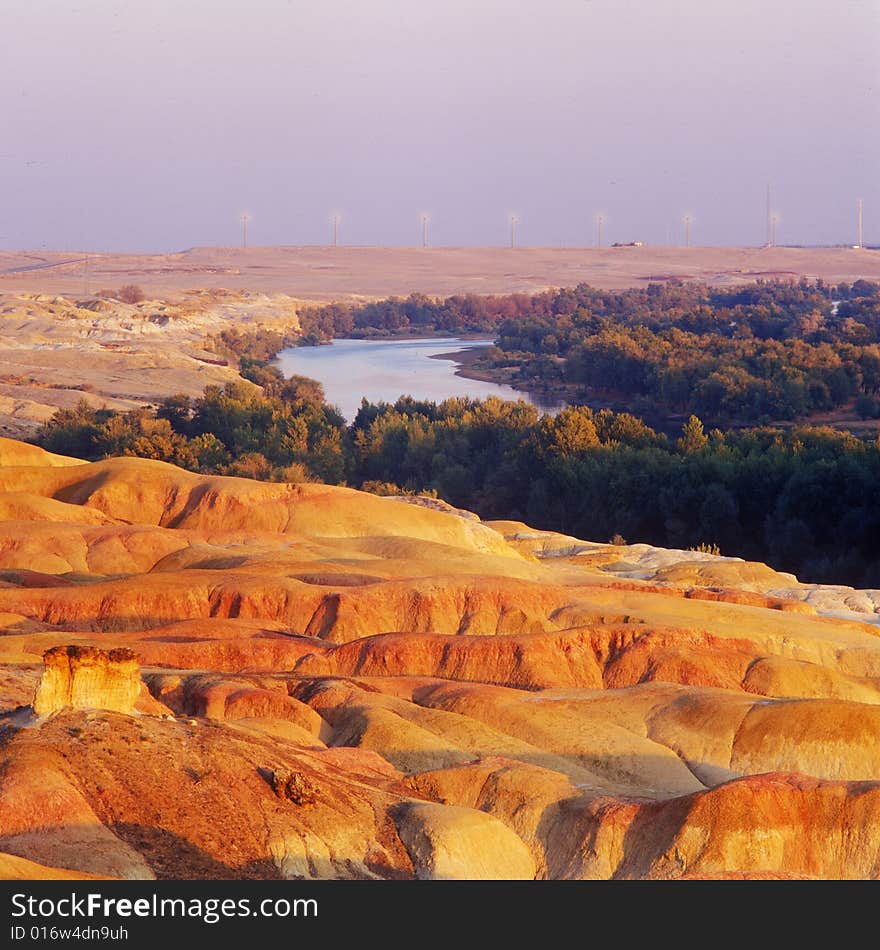 A river with forest and red rock on its sides . A view in Xinjiang China. A river with forest and red rock on its sides . A view in Xinjiang China