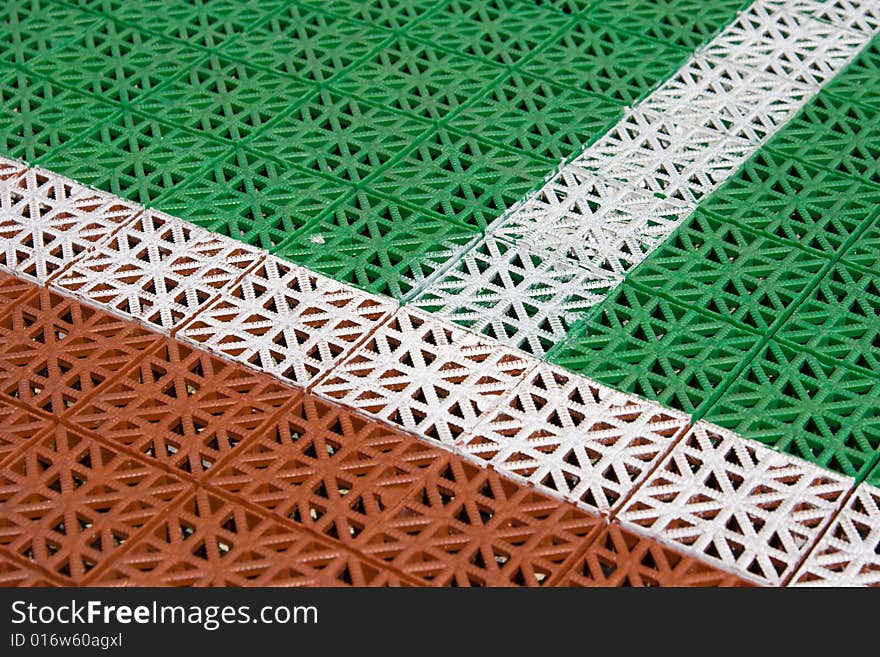 Artificial tennis court cover, brown and green with white lines, close-up