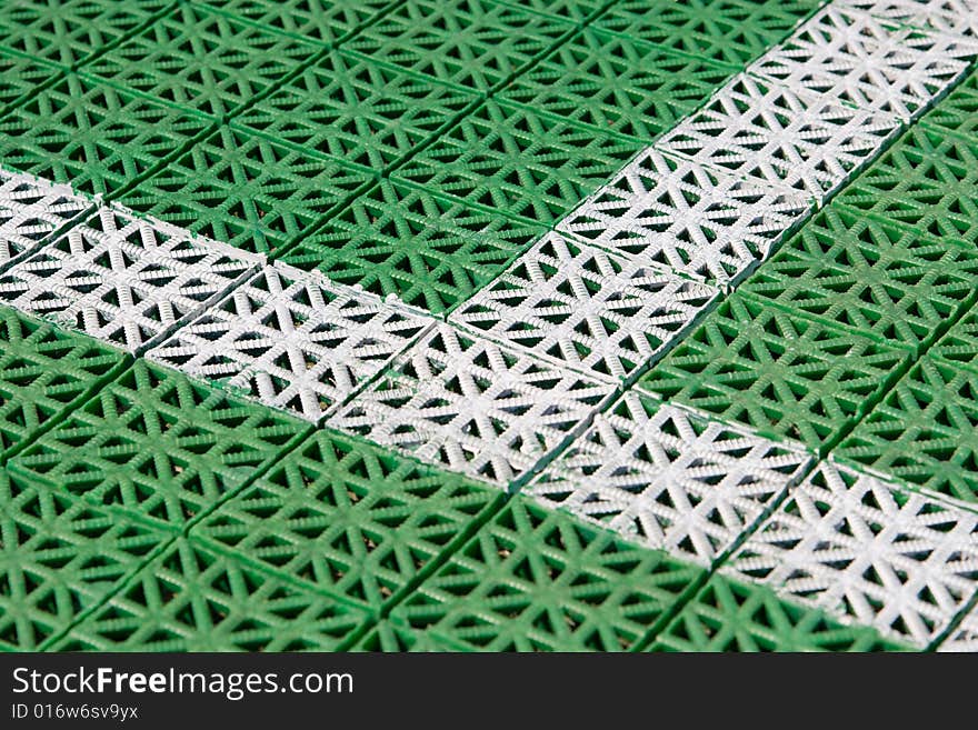 Artificial tennis court cover, green with white lines, close-up