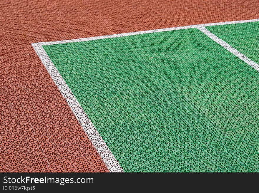 Artificial tennis court cover, brown and green with white lines, close-up