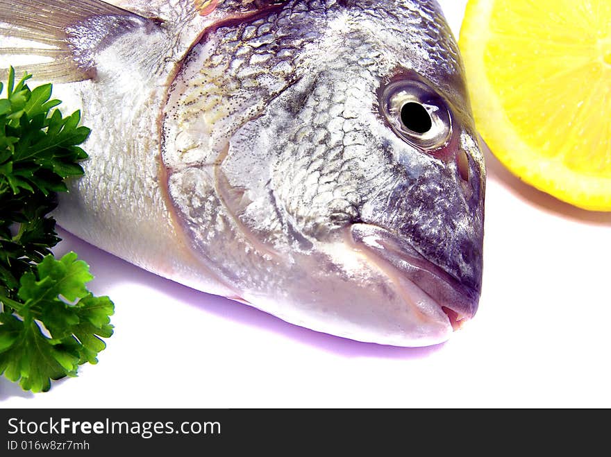 Detail view of a raw sea bream with parsley and lemon. Detail view of a raw sea bream with parsley and lemon.