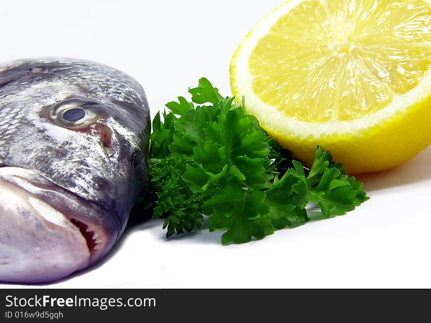 Detail view of a raw sea bream with parsley and lemon. Detail view of a raw sea bream with parsley and lemon.