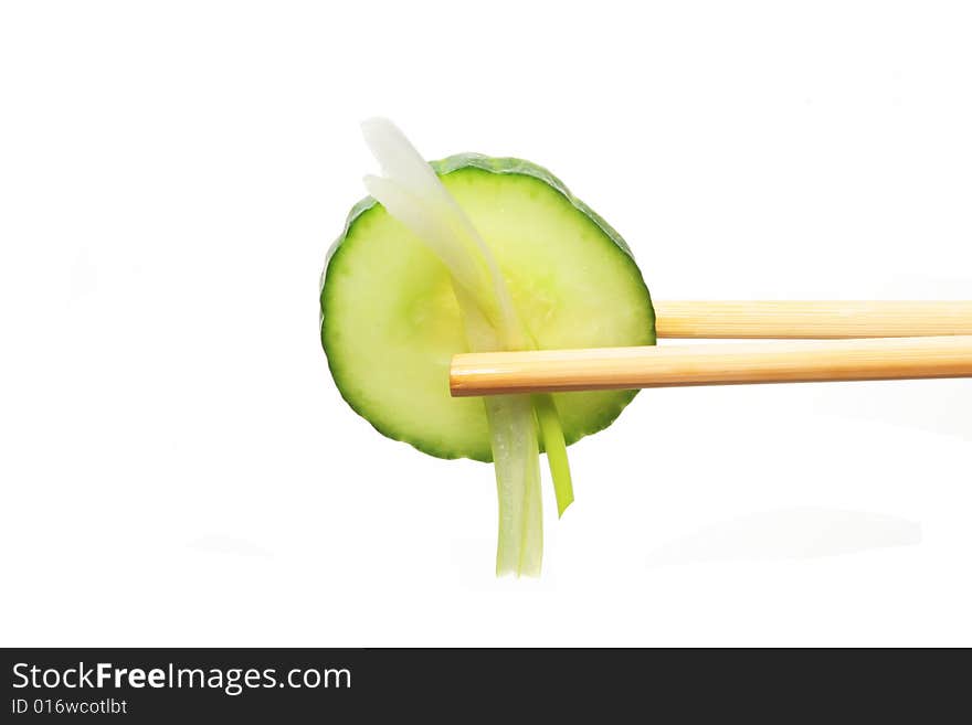 Cucumber and spring onion in chopsticks against white