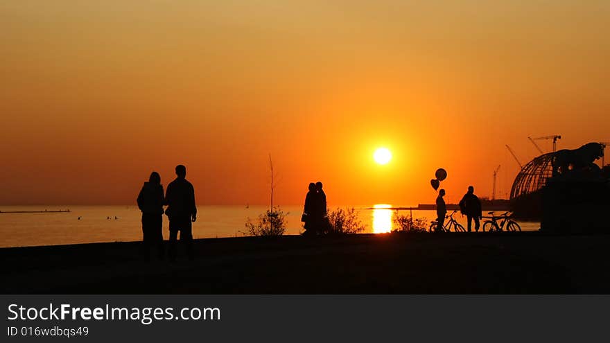 People's silhouette in sunset on the coast of sea