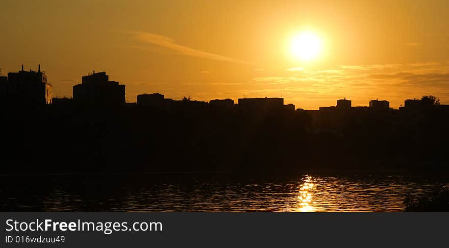 Silhouette of city in sunset on the coast of sea