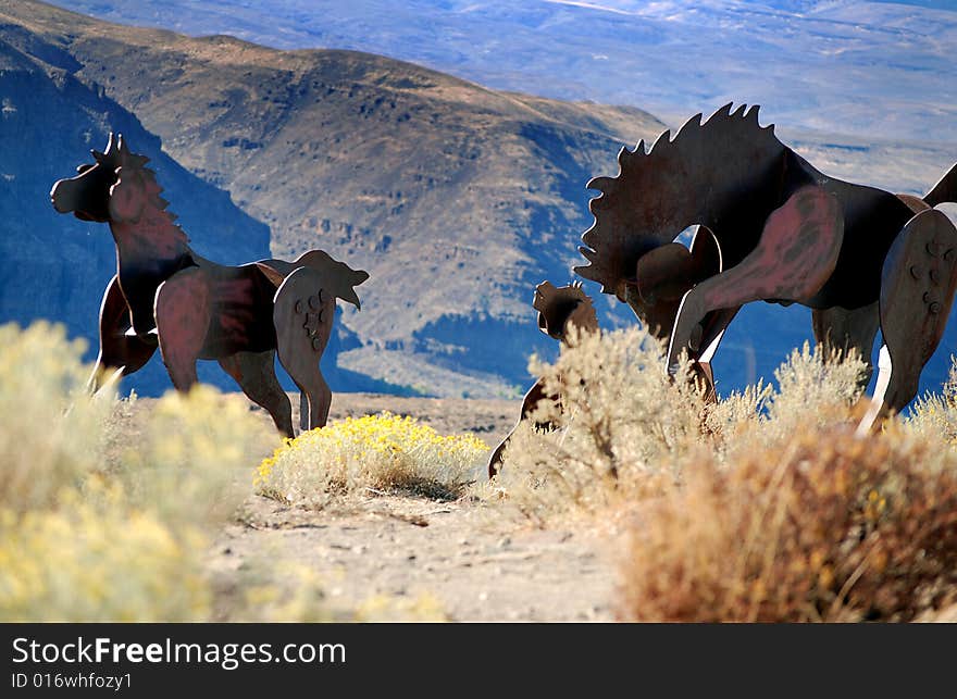 Metal horses galloping high up on a ridge. Metal horses galloping high up on a ridge