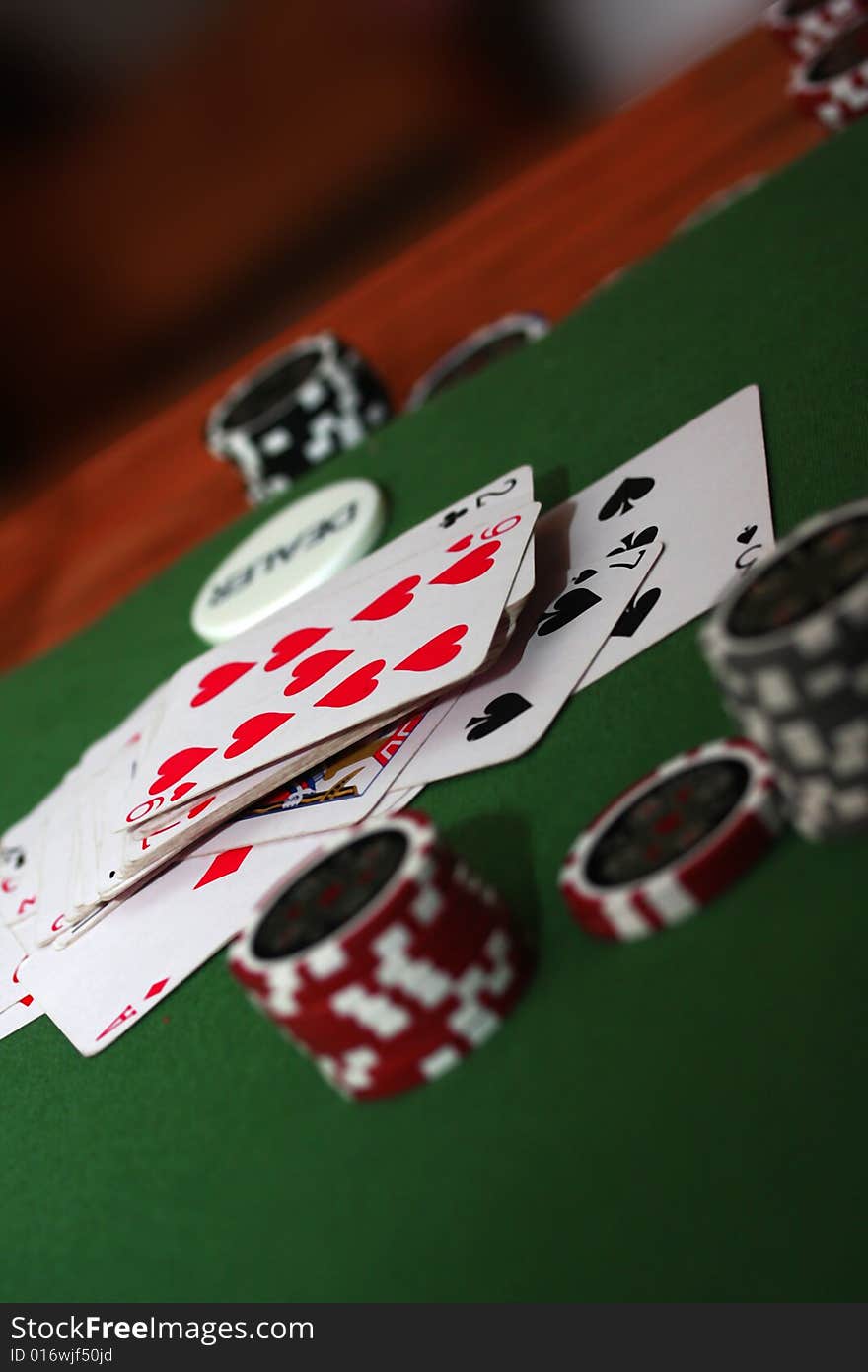 Poker chips in different colours on green background with playing cards. Poker chips in different colours on green background with playing cards