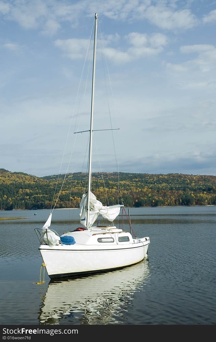 A small white sail boat near the shore