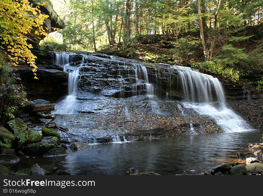 View of waterfall in the woods at the beginning of autumn as the leaves are beginning to turn color. View of waterfall in the woods at the beginning of autumn as the leaves are beginning to turn color.