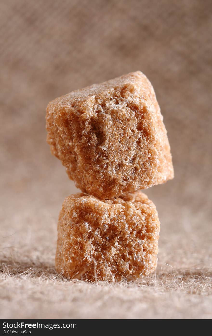 Two brown sugar cubes on hessian background, macro, shallow DOF