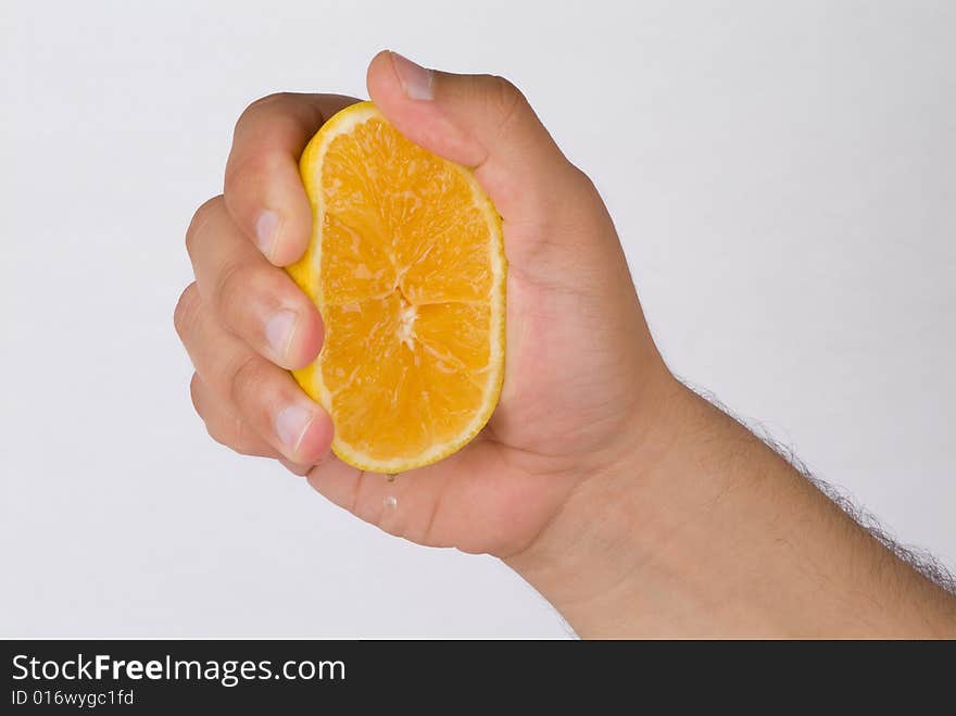 A hand squeezing for orange drops. A hand squeezing for orange drops