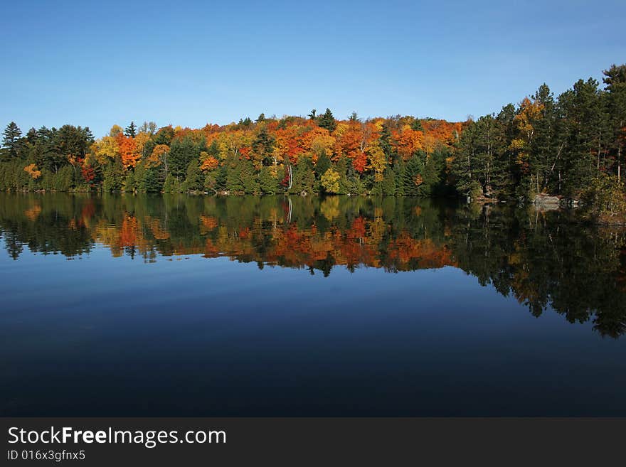 A very calm autumn morning with beautiful colors reflected in mirror like lake. A very calm autumn morning with beautiful colors reflected in mirror like lake