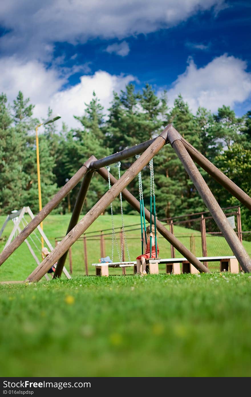 Child at big wooden swing at the forest background. Child at big wooden swing at the forest background