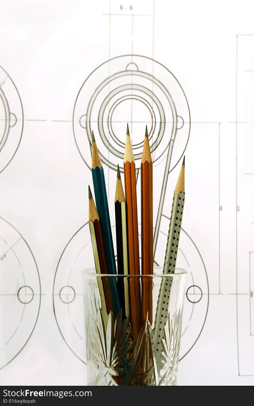 Pencils in a glass against the machine-building drawing