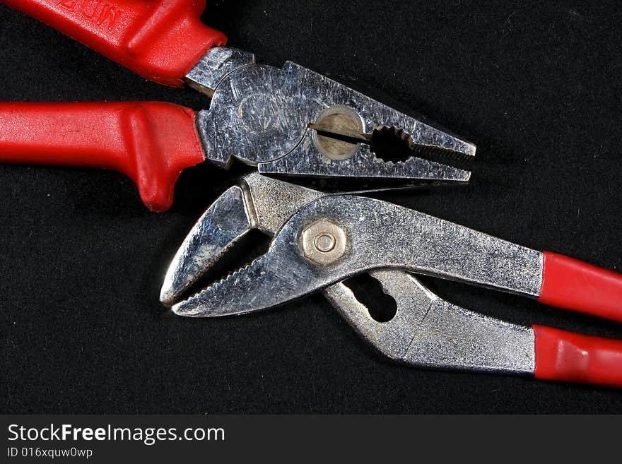 Pliers with red neck on a black background. Pliers with red neck on a black background