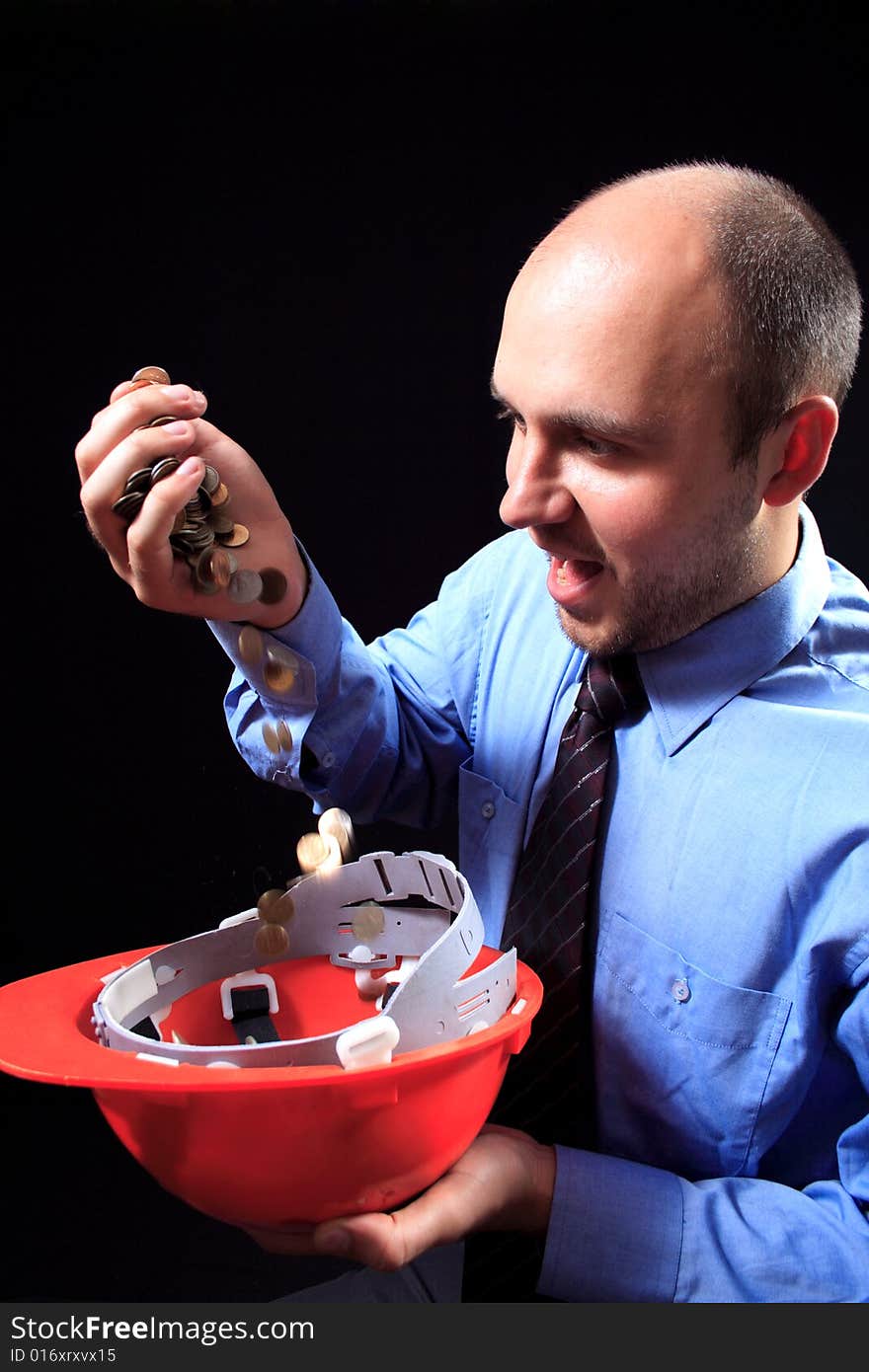 Man in a shirt and a tie fills coins, on a black background. Man in a shirt and a tie fills coins, on a black background