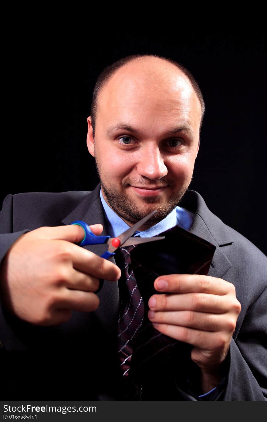 Man in a business suit scissors the tie, on a black background. Man in a business suit scissors the tie, on a black background