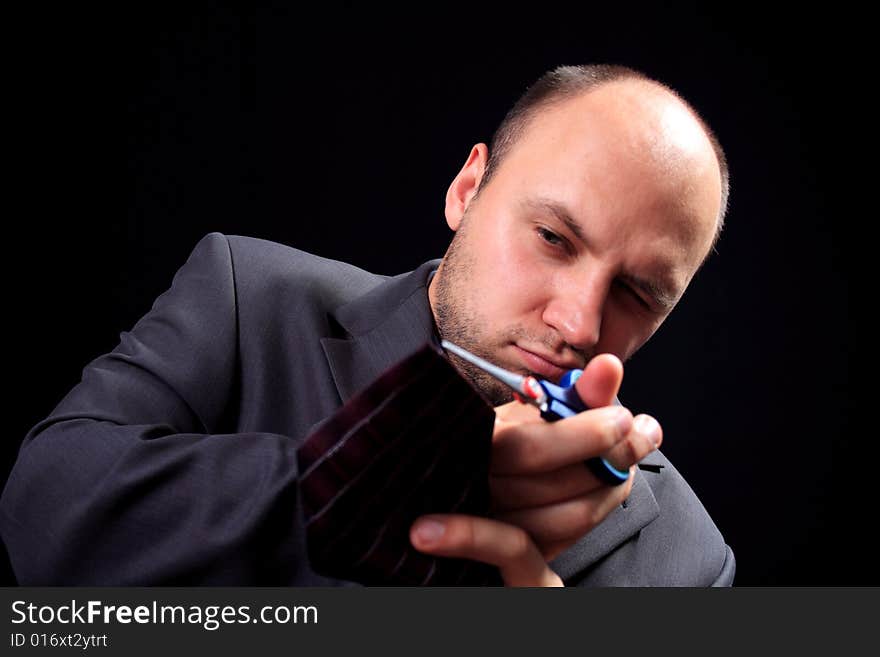 Man in a business suit scissors the tie, on a black background. Man in a business suit scissors the tie, on a black background