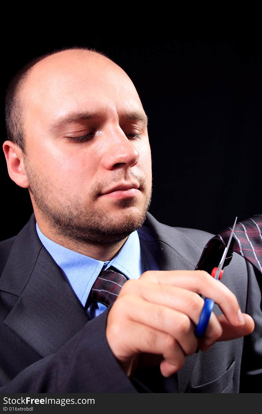 Man in a business suit scissors the tie, on a black background. Man in a business suit scissors the tie, on a black background