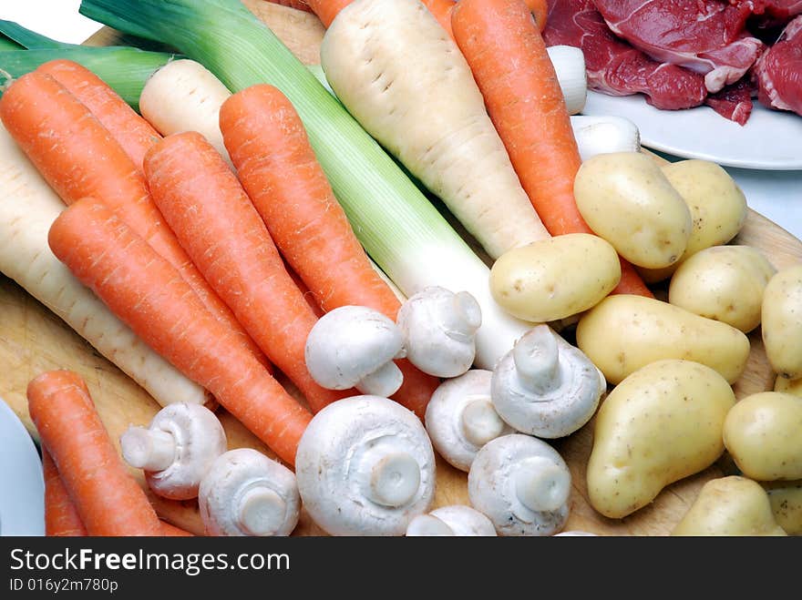 A close up selection of fresh meat and vegetables on a chopping board. A close up selection of fresh meat and vegetables on a chopping board.