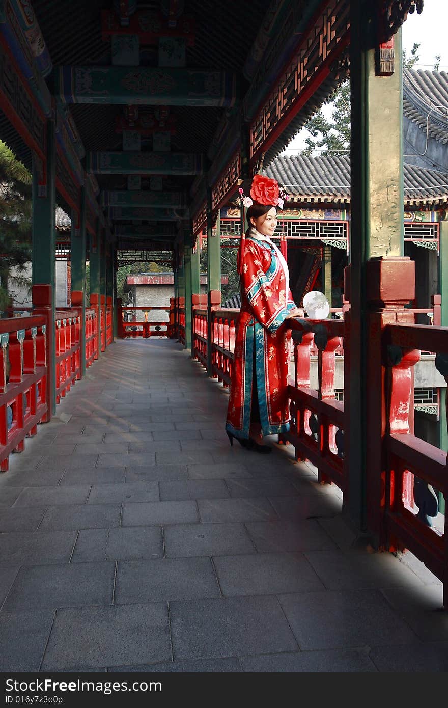 A girl in Chinese ancient dress stands in the long corridor of the royal garden. Chinese on the fan is meant and missed. A girl in Chinese ancient dress stands in the long corridor of the royal garden. Chinese on the fan is meant and missed.