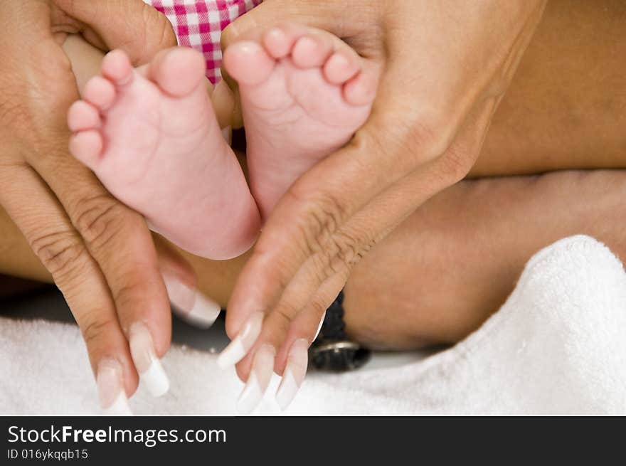 Mommy holding baby's feet against white background. Mommy holding baby's feet against white background