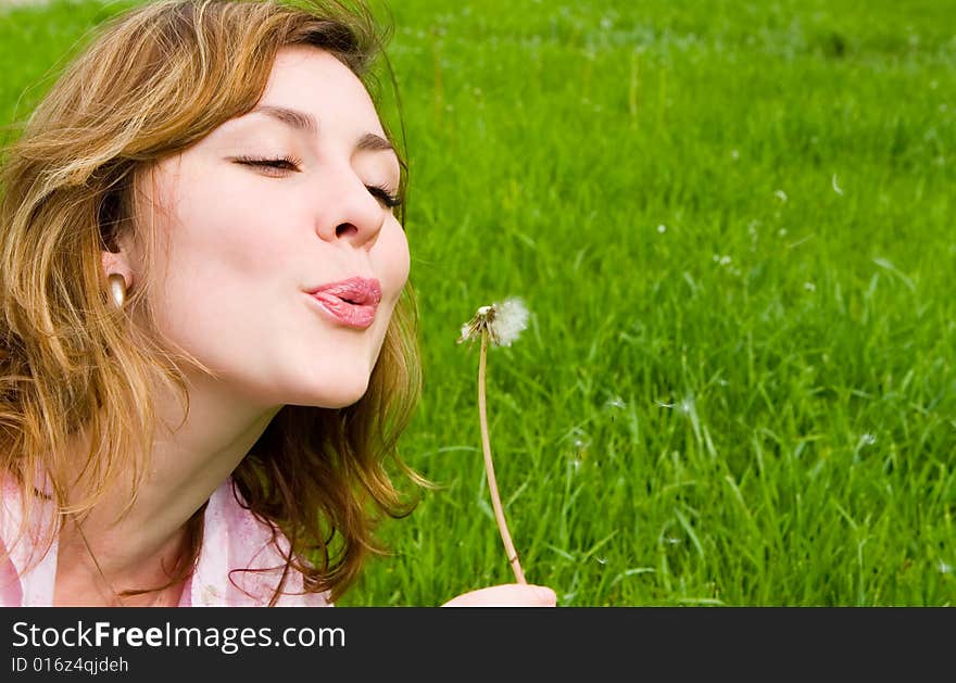 Young girl blowing on the dandelion