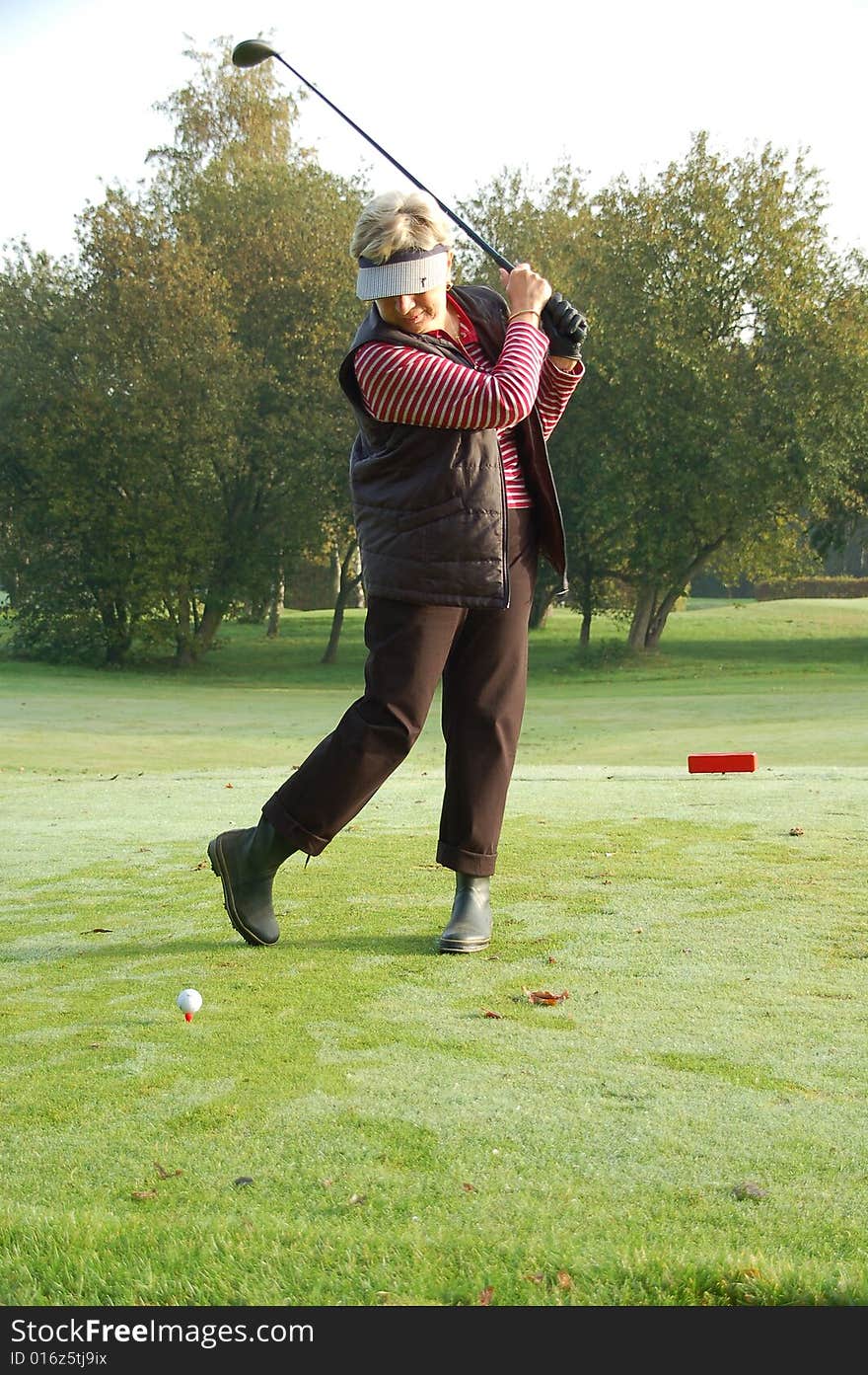 Female golfer teeing off on the green